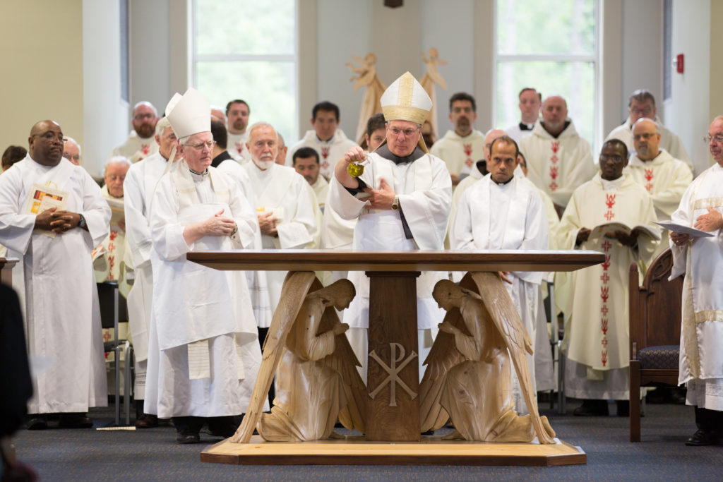 Bishop Hartmayer pours a cruet of chrism oil onto the top of the new altar.