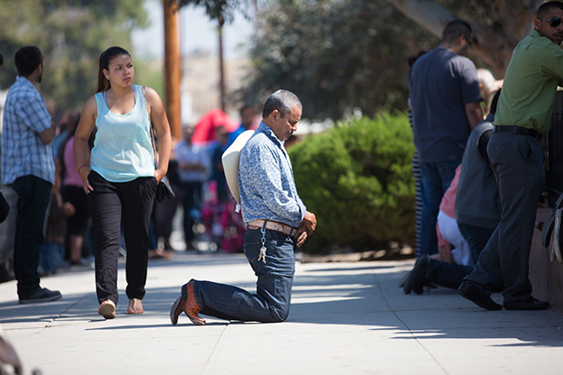 Man kneeliing outside crowded church in Perris California 