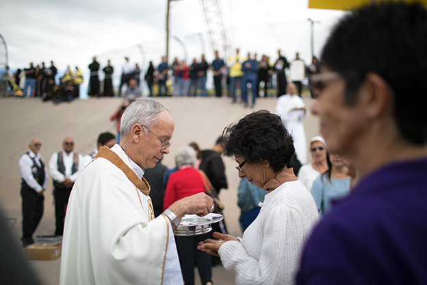 Priest gives communion at Catholic Mass on the border 