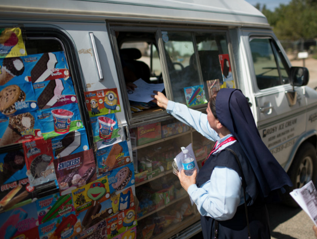 A sister hands a paper to an ice cream truck driver