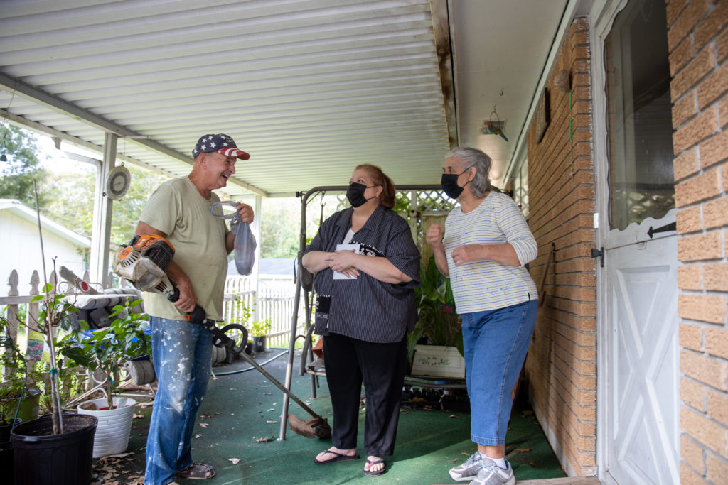 Father Ron Foshage talks with two women on a porch