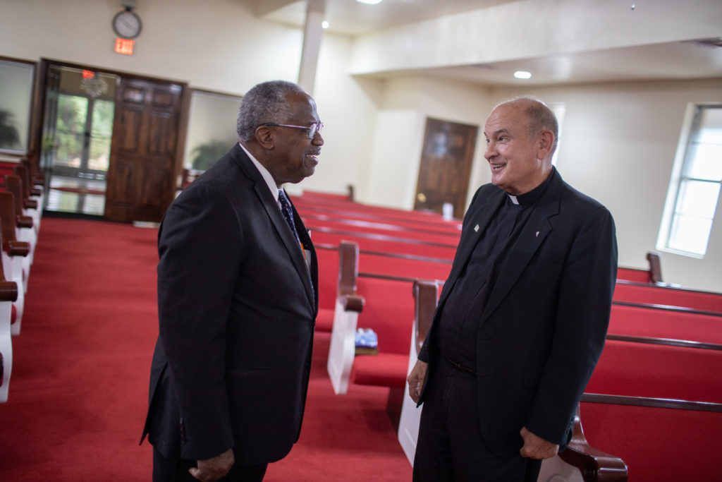 Father Ron Foshage and Pastor Lyons talk in a church