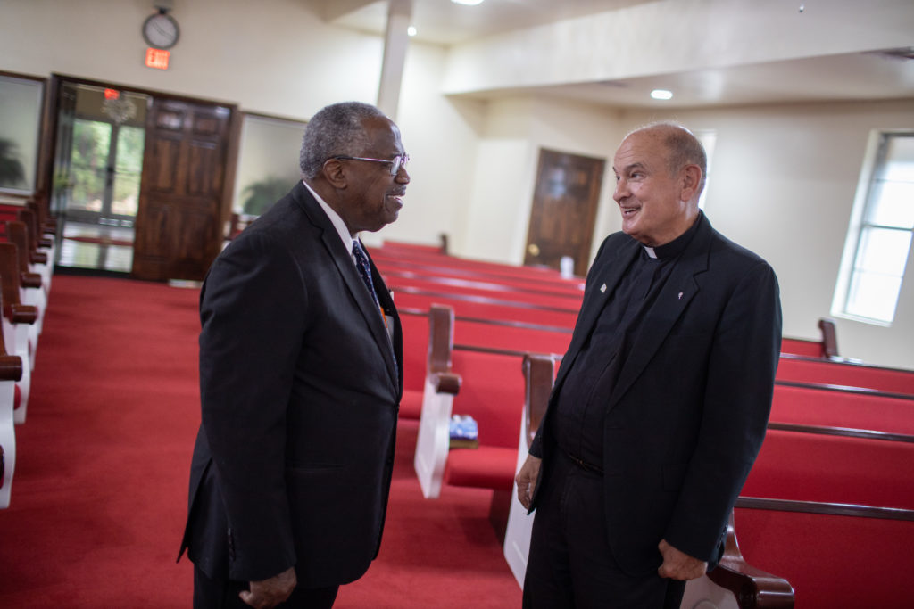 Father Ron Foshage and Pastor Lyons talk in a church