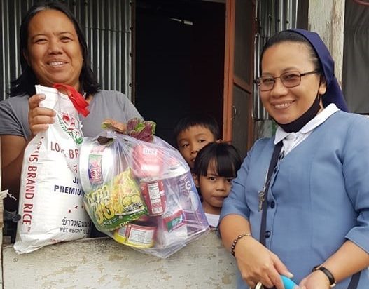 Catholic Sister Saturnina Caccam, SJBP, delivers food to a family struggling amid COVID-19.